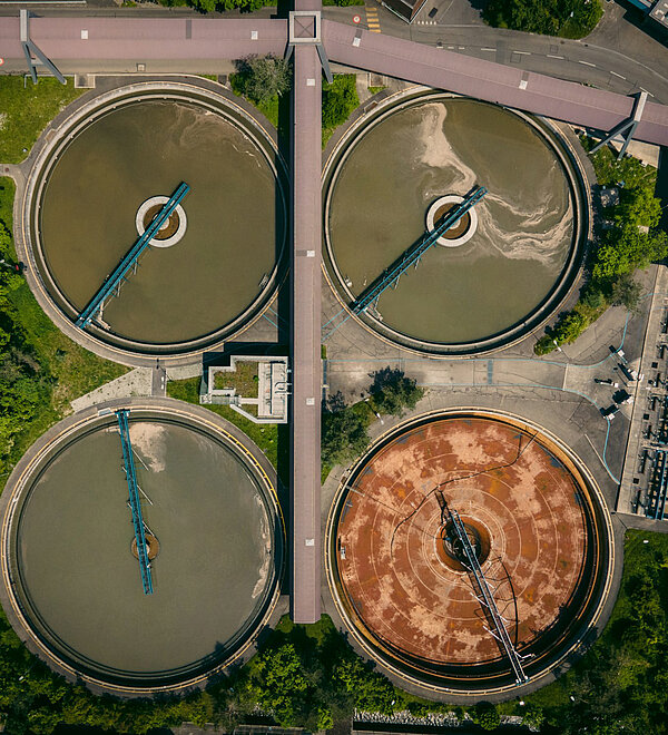 [Translate to English:] Luftaufnahme einer Kläranlage mit kreisförmigen Abwasserklärbecken
